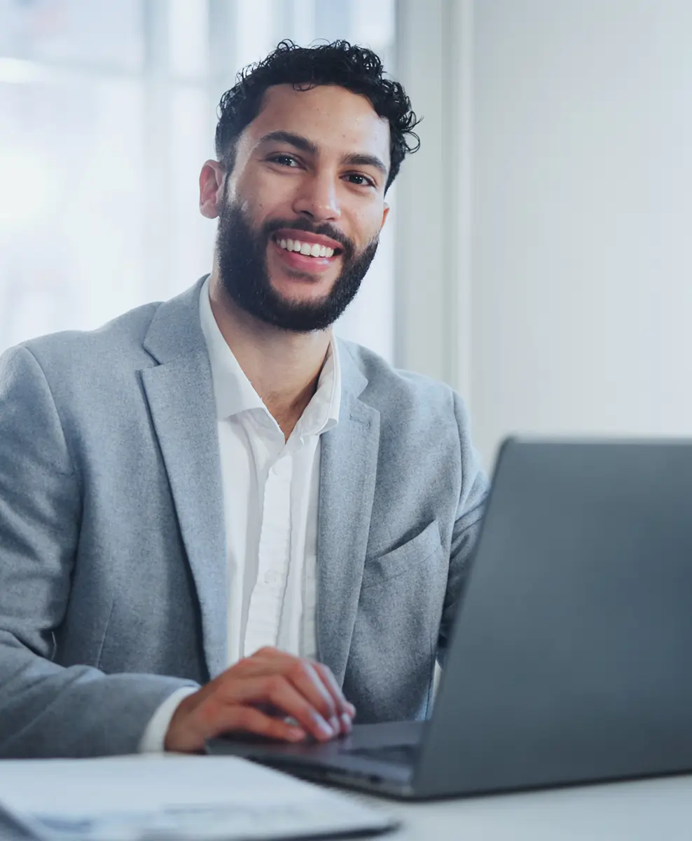 Happy client working on a laptop in a modern office, satisfied with Odoo ERP services, surrounded by business documents and reports.