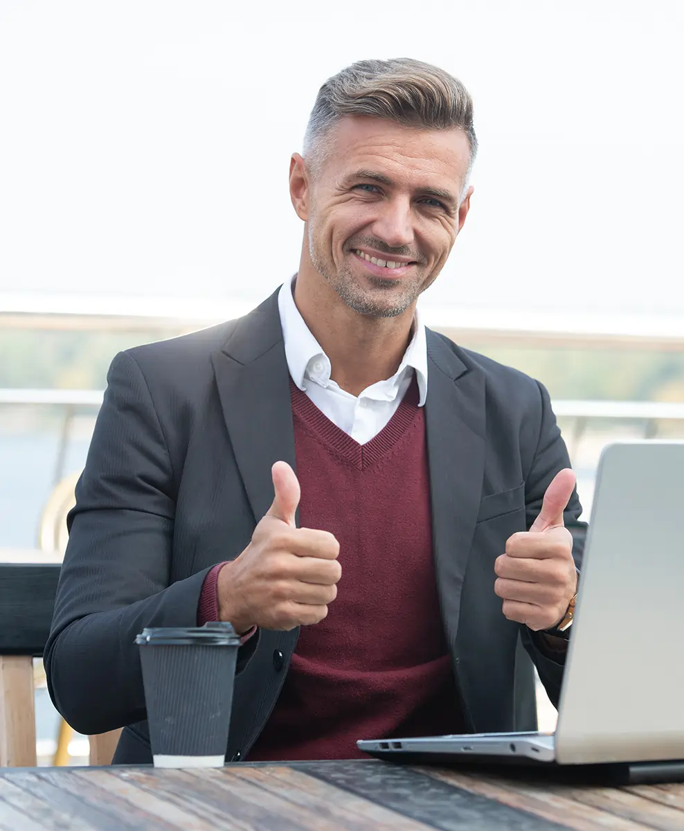 Happy businessman giving thumbs up while working on laptop, showing satisfaction with Odoo ERP solutions