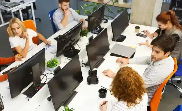 Group of young business professionals collaborating in a modern coworking office, reflecting dynamic team culture and collaborative working environment in an IT company.